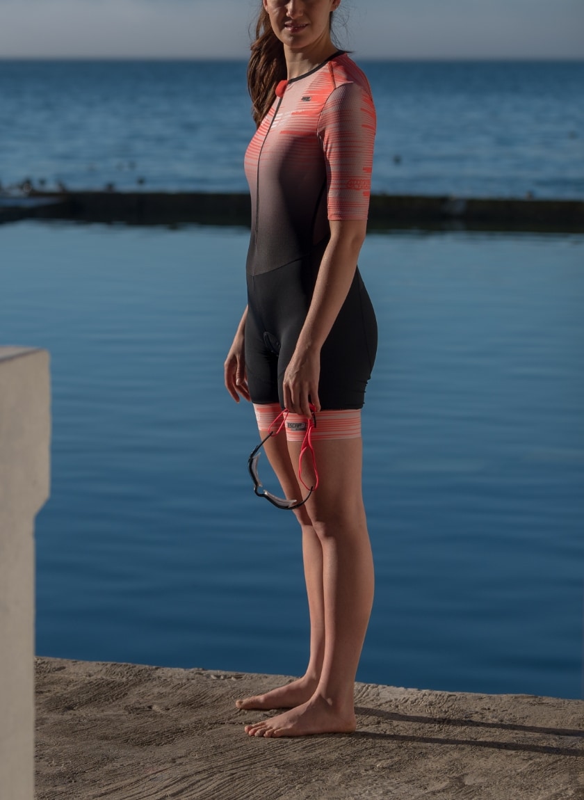 Female triathlete wearing the womens Escape sleeved trisuit in the Input orange design by Enjoy.cc